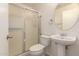 Bathroom featuring glass shower, a toilet, and pedestal sink with a round mirror at 8104 S 73Rd Dr, Laveen, AZ 85339