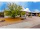 Single-story home featuring a covered porch, landscaped front yard, flowering tree, and convenient carport at 8143 E Whitton Ave, Scottsdale, AZ 85251