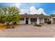 Charming single-story home featuring a covered porch, landscaped front yard, and beautiful flowering tree at 8143 E Whitton Ave, Scottsdale, AZ 85251