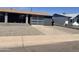 Modern single-story home with a gray exterior, stone landscaping, and a transparent glass garage door at 8520 E Mackenzie Dr, Scottsdale, AZ 85251
