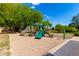 Community playground featuring slides and climbing structure surrounded by mature trees and sand at 870 E Megan St, Gilbert, AZ 85295