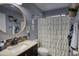 Bathroom vanity with dark cabinetry, marble countertop, round mirror, and white shower curtain at 10308 E Osage Ave, Mesa, AZ 85212