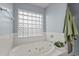 Bright bathroom featuring a luxurious soaking tub with jets and a glass block window at 11405 W Windsor Ave, Avondale, AZ 85392