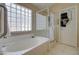 Large soaking tub with glass block window and walk-in shower stall at 14298 W Amelia Ave, Goodyear, AZ 85395