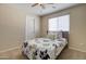 Cozy bedroom with a ceiling fan, window with blinds, and floral bedspread at 14298 W Amelia Ave, Goodyear, AZ 85395