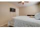 This neutral toned bedroom features a ceiling fan and a wall-mounted TV at 14298 W Amelia Ave, Goodyear, AZ 85395
