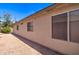View of the side of the home, showcasing neutral stucco and a gravel border, as well as the windows with closed blinds at 14298 W Amelia Ave, Goodyear, AZ 85395