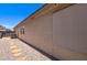 Side exterior view of the property, featuring neutral stucco and a stone walkway, showing the AC Unit and sun shade at 14298 W Amelia Ave, Goodyear, AZ 85395