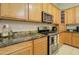 Close-up of a kitchen with wooden cabinetry, granite countertops, and stainless steel appliances at 14298 W Amelia Ave, Goodyear, AZ 85395