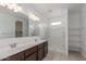 Bright bathroom featuring a double vanity, large mirror, and a separate shower with white tile surround at 16938 N Verde Pl, Maricopa, AZ 85138