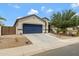 Charming one-story home featuring a blue garage door, desert landscaping, and a welcoming entrance at 18366 N Arbor Dr, Maricopa, AZ 85138