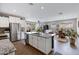 Open-concept kitchen with stainless steel appliances, white cabinetry, granite countertops, and central island overlooking the living area at 18366 N Arbor Dr, Maricopa, AZ 85138