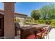 Outdoor kitchen featuring a built-in barbecue, bar seating, and lush landscaping views at 30135 N 129Th Gln, Peoria, AZ 85383