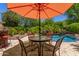 Poolside dining with umbrella, lush greenery, and tranquil pool views for outdoor enjoyment at 30135 N 129Th Gln, Peoria, AZ 85383
