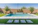 Backyard pool surrounded by lush green turf, decorative pavers, a brick wall, and beautiful landscaping at 3260 W Caleb Rd, Phoenix, AZ 85083