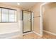 Bathroom featuring a bathtub, shower with glass door, window, and neutral tile flooring at 3443 E Jasper Dr, Gilbert, AZ 85296