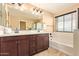 Well-lit bathroom featuring double sinks, vanity, large mirror, and a separate bathtub at 3443 E Jasper Dr, Gilbert, AZ 85296