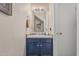 Compact half-bathroom features a vanity with a navy blue cabinet, a large mirror and a door to the side at 3488 S Bowman Rd, Apache Junction, AZ 85119