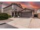 Inviting two-story home with a two-car garage and neutral colored stucco facade, set against a fiery sunset backdrop at 3488 S Bowman Rd, Apache Junction, AZ 85119