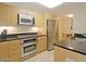 Modern kitchen featuring stainless steel appliances, light wood cabinets, and black countertops at 4808 N 24Th St # 204, Phoenix, AZ 85016