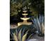 Elegant three-tier fountain amidst lush landscaping, softly illuminated for evening ambiance at 5336 E Gloria Ln, Cave Creek, AZ 85331