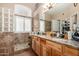 Bathroom with a dual-sink vanity, wood cabinetry, a tile shower, and a glass block window at 5536 E Gable Ave, Mesa, AZ 85206