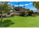 Expansive backyard with green lawn, mature trees, and a glimpse of the mountain view in the distance at 6055 E Vernon Ave, Scottsdale, AZ 85257