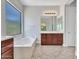 Bright bathroom featuring a soaking tub under a window and dark wood cabinets at 6914 W Juana Dr, Peoria, AZ 85383