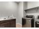 This laundry room is well-equipped with a sink, dark wood cabinets, and stainless steel appliances at 7216 N 124Th Ln, Glendale, AZ 85307