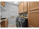 Functional laundry room with wood cabinets, modern washer/dryer and a sink at 9708 E Pampa Ave, Mesa, AZ 85212