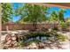 Beautiful backyard featuring a rock-lined pond and a variety of lush trees and plantings at 12375 W Meadowbrook Ave, Avondale, AZ 85392