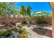Serene backyard with rock-lined pond, waterfall, and patio seating under a colorful umbrella at 12375 W Meadowbrook Ave, Avondale, AZ 85392