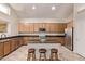 Well-lit kitchen features stainless steel appliances, wood cabinets, a center island with barstool seating, and tile flooring at 12375 W Meadowbrook Ave, Avondale, AZ 85392