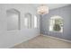 Light-filled room features neutral walls, tiled floors, inset shelves, and a modern chandelier at 13630 W Redfield Rd, Surprise, AZ 85379