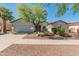 Charming single-story home featuring a well-manicured yard, two-car garage, and desert landscaping at 13630 W Redfield Rd, Surprise, AZ 85379