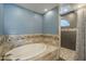 Luxurious bathroom with a soaking tub, decorative tile accents, and a separate shower at 15828 N 10Th Pl, Phoenix, AZ 85022