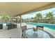 Covered patio area with dining table overlooking a backyard oasis with a pool, spa, and lush landscaping at 16197 N 157Th Ave, Surprise, AZ 85374