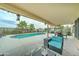 Inviting covered patio with comfortable seating, adjacent to a sparkling swimming pool and lush palm trees at 16197 N 157Th Ave, Surprise, AZ 85374