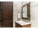 Elegant bathroom features a carved wood mirror over a marble sink with a dark wood door at 1659 N Channing --, Mesa, AZ 85207