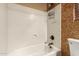 Bathtub with white surround and shower, next to toilet and decorative wall at 18434 E El Buho Pequeno Rd, Gold Canyon, AZ 85118