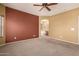 Bright, carpeted primary bedroom with a ceiling fan, view into the primary bath, and fresh, neutral paint at 18434 E El Buho Pequeno Rd, Gold Canyon, AZ 85118