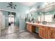 Well-lit bathroom featuring a double vanity, tiled floors, and a seamless transition to the walk-in closet at 18547 W Sweet Acacia Dr, Goodyear, AZ 85338