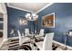 Contemporary dining room featuring a glass table, stylish chandelier, zebra rug, and elegant wall decor at 18547 W Sweet Acacia Dr, Goodyear, AZ 85338