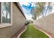 View of a low maintenance backyard with artificial turf and gravel alongside a beige home exterior and block wall at 28232 N Abby Cir, San Tan Valley, AZ 85143