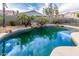 Sparkling backyard pool with rock features, palms, and view of the surrounding neighborhood at 28232 N Abby Cir, San Tan Valley, AZ 85143