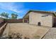 View of a mostly dirt backyard and a home with a covered patio, hose, and small window at 30100 N Sunray Dr, San Tan Valley, AZ 85143