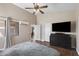 Bright bedroom with wood-look tile flooring, ceiling fan, television, and ensuite bathroom access at 30100 N Sunray Dr, San Tan Valley, AZ 85143