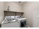 Bright laundry room with modern, front-loading washer and dryer, and convenient overhead shelving at 30100 N Sunray Dr, San Tan Valley, AZ 85143