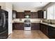 Stylish kitchen featuring dark wood cabinets, granite countertops, and modern stainless steel appliances at 3952 E Frances Ln, Gilbert, AZ 85295