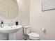 A well-lit bathroom features a pedestal sink, round mirror, toilet, and window with blinds at 4044 S 58Th Ln, Phoenix, AZ 85043